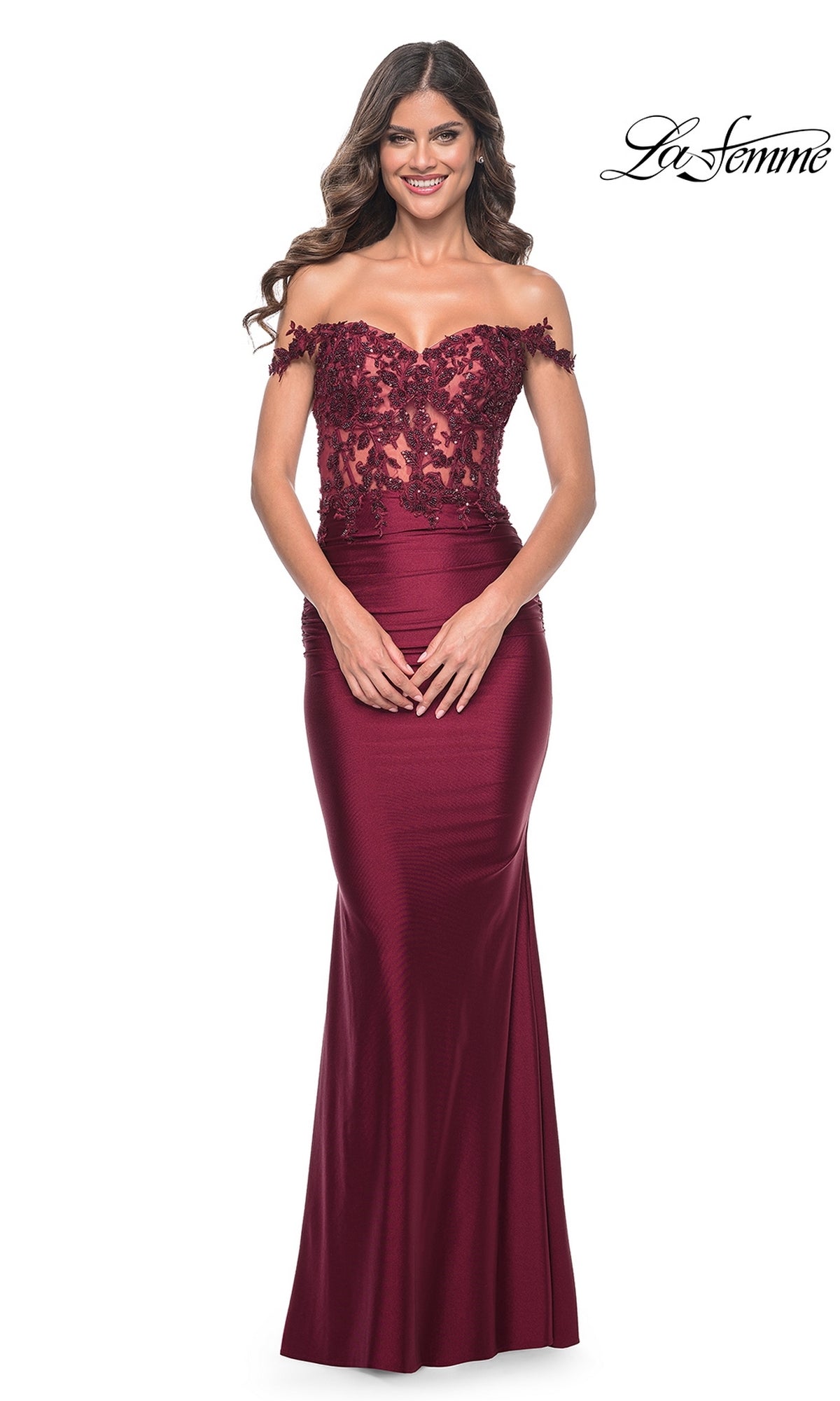 A woman wears the La Femme Off-the-Shoulder Long Prom Dress 32302 in burgundy, featuring a beaded floral lace bodice and fitted satin skirt. The